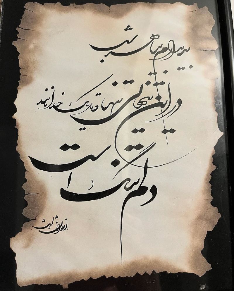 Calligraphie persane à l’encre noire sur un papier aux bords brûlés